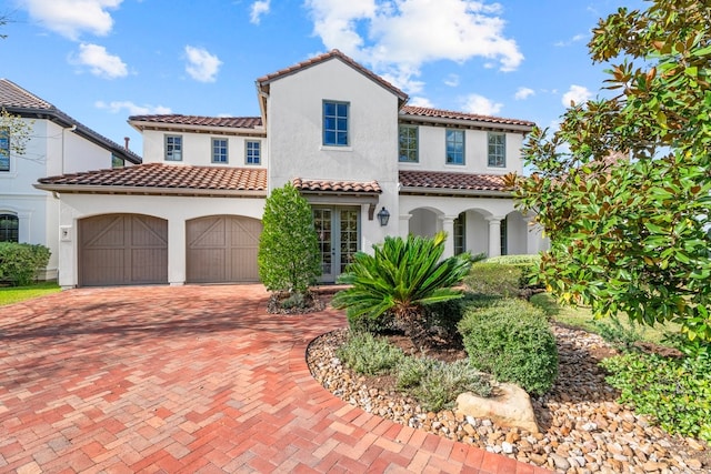 mediterranean / spanish house with a garage and french doors