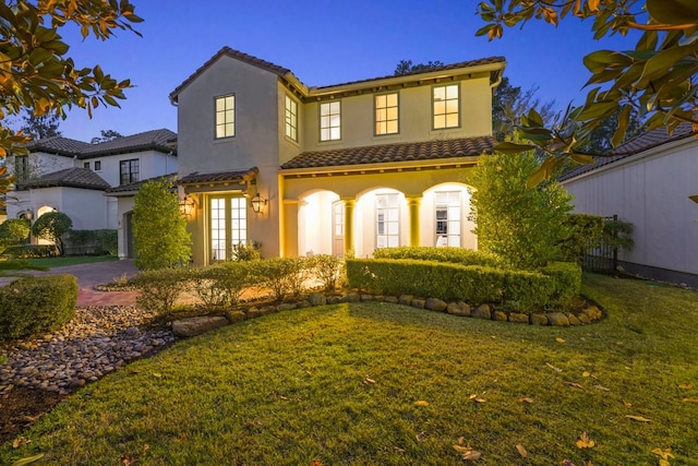 mediterranean / spanish house featuring a front lawn and french doors