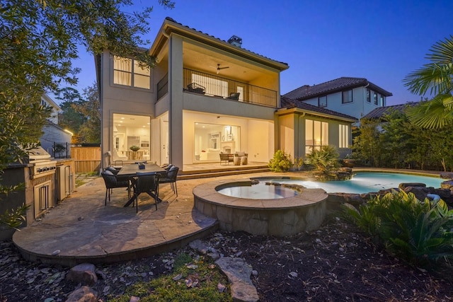 back house at dusk featuring a patio area, a balcony, and a pool with hot tub