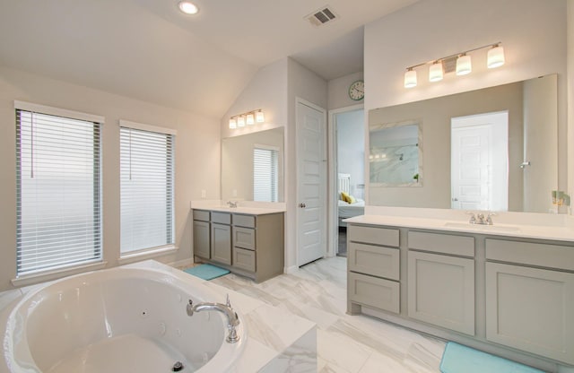 bathroom featuring vanity, a bath, and vaulted ceiling