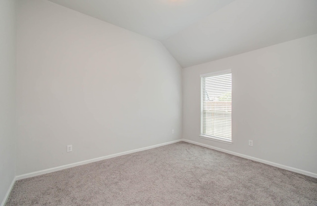 carpeted empty room featuring lofted ceiling