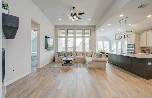 living room with ceiling fan, sink, and light hardwood / wood-style floors