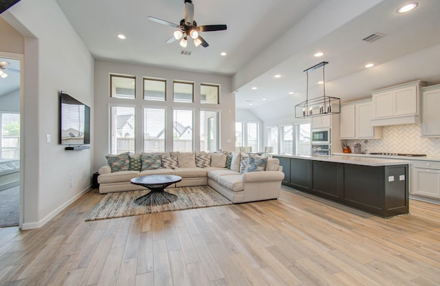 living room featuring light hardwood / wood-style flooring and ceiling fan with notable chandelier