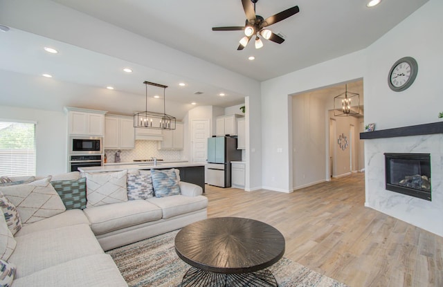 living room with ceiling fan, light hardwood / wood-style flooring, and a high end fireplace