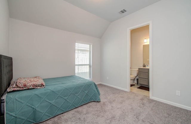 carpeted bedroom featuring ensuite bathroom and vaulted ceiling