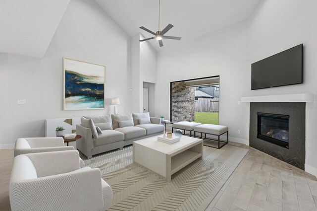 living room featuring ceiling fan, light wood-type flooring, and high vaulted ceiling