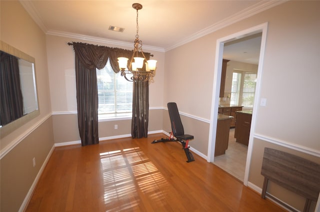 unfurnished dining area with crown molding, a notable chandelier, and hardwood / wood-style flooring