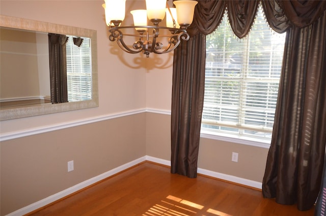 unfurnished room featuring hardwood / wood-style flooring and an inviting chandelier