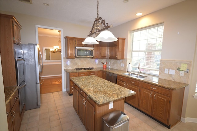 kitchen with sink, hanging light fixtures, backsplash, a kitchen island, and appliances with stainless steel finishes