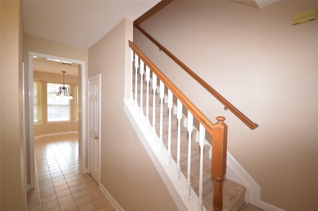 stairs featuring a chandelier and tile patterned flooring