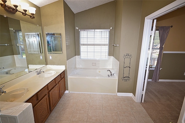 bathroom featuring a bath, tile patterned floors, vaulted ceiling, a textured ceiling, and vanity