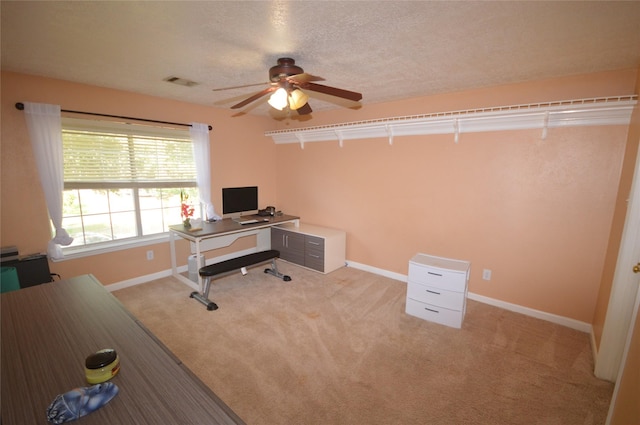 office space featuring a textured ceiling, ceiling fan, and light carpet