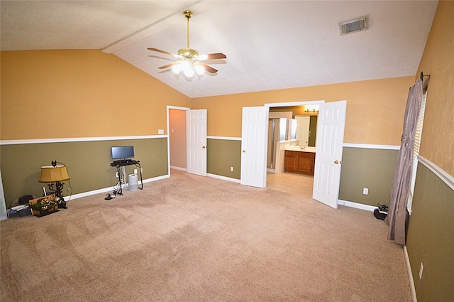 interior space featuring connected bathroom, ceiling fan, light colored carpet, and vaulted ceiling