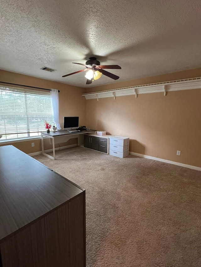 unfurnished office with a textured ceiling, ceiling fan, and carpet