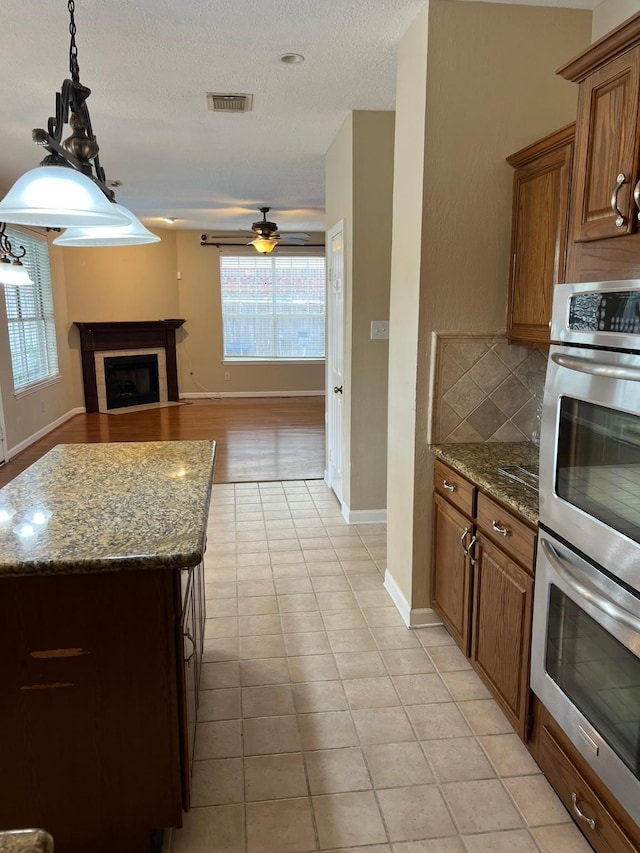 kitchen featuring light stone countertops, a kitchen island, stainless steel double oven, and a textured ceiling