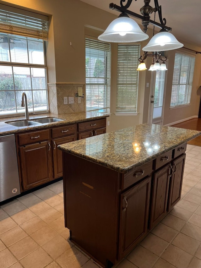 kitchen with decorative light fixtures, sink, a center island, stainless steel dishwasher, and dark brown cabinetry