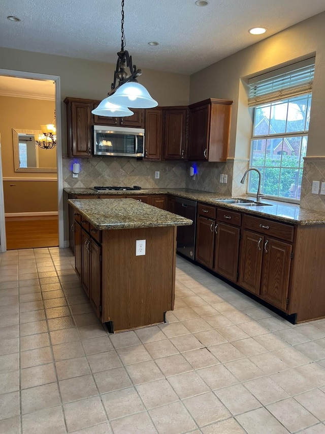 kitchen with a kitchen island, tasteful backsplash, sink, light stone counters, and stainless steel appliances