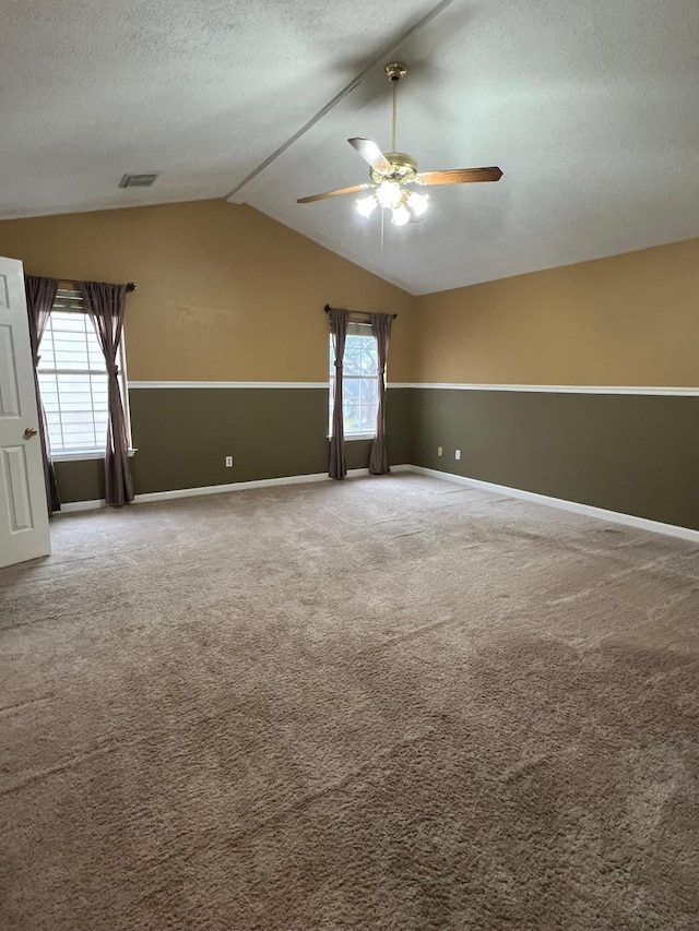 empty room featuring lofted ceiling, ceiling fan, a textured ceiling, and carpet flooring