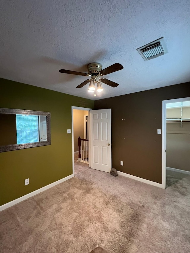 unfurnished bedroom with ceiling fan, carpet flooring, and a textured ceiling