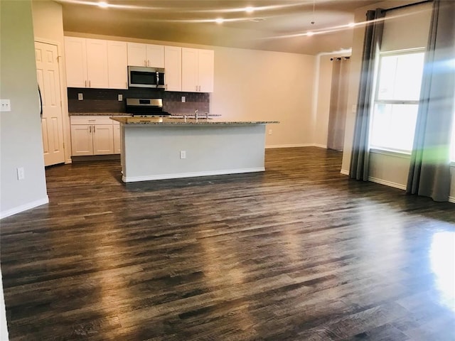 kitchen featuring dark hardwood / wood-style flooring, white cabinetry, a center island with sink, and appliances with stainless steel finishes