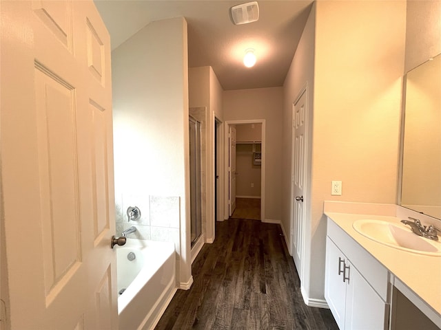 bathroom featuring plus walk in shower, vanity, and wood-type flooring