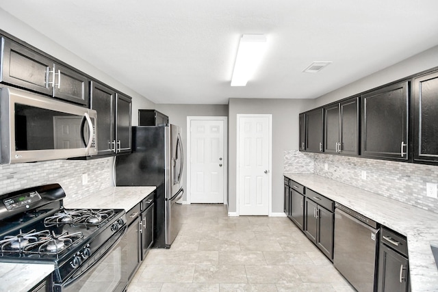 kitchen with tasteful backsplash, light stone countertops, and appliances with stainless steel finishes