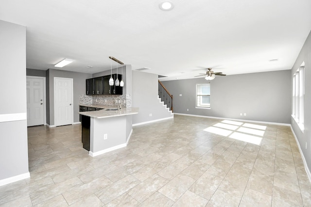 kitchen with kitchen peninsula, decorative backsplash, ceiling fan, sink, and decorative light fixtures