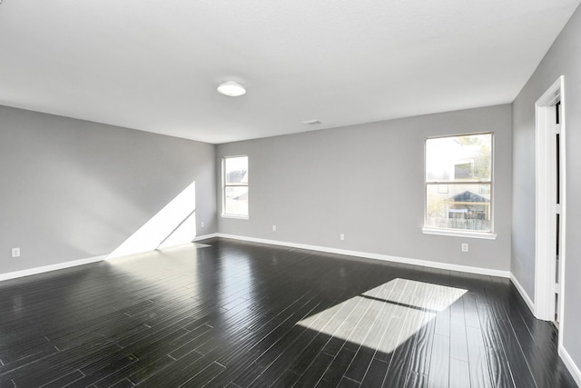 empty room featuring dark hardwood / wood-style flooring and a healthy amount of sunlight