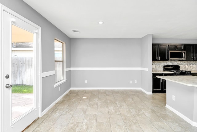 kitchen featuring light stone countertops, gas stove, and tasteful backsplash