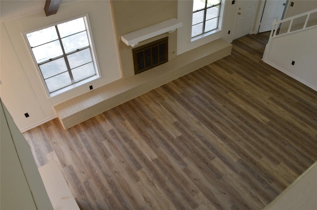 unfurnished living room with beamed ceiling, dark wood-type flooring, and a wealth of natural light