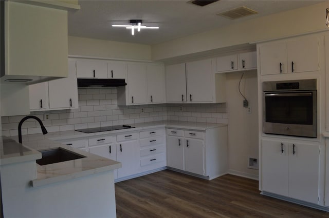 kitchen with stainless steel oven, sink, tasteful backsplash, black electric cooktop, and white cabinets