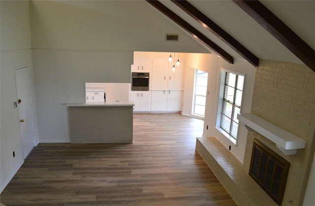 unfurnished living room with high vaulted ceiling, beamed ceiling, dark wood-type flooring, and a brick fireplace