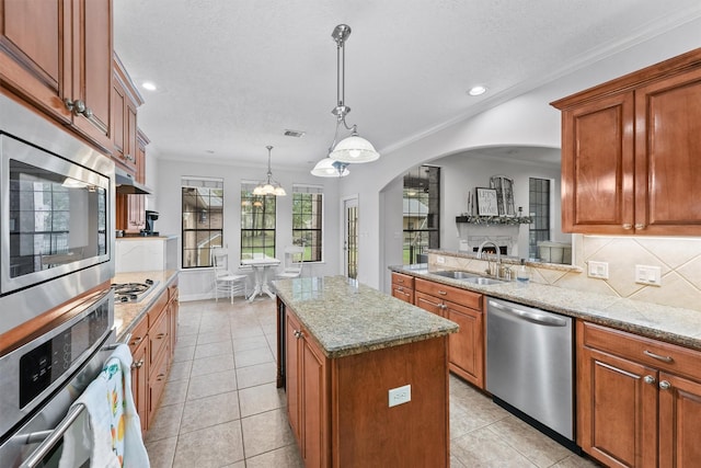 kitchen with appliances with stainless steel finishes, sink, light tile patterned floors, a center island, and hanging light fixtures