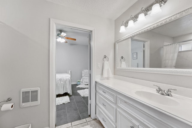 bathroom with ceiling fan, tile patterned flooring, heating unit, a textured ceiling, and vanity