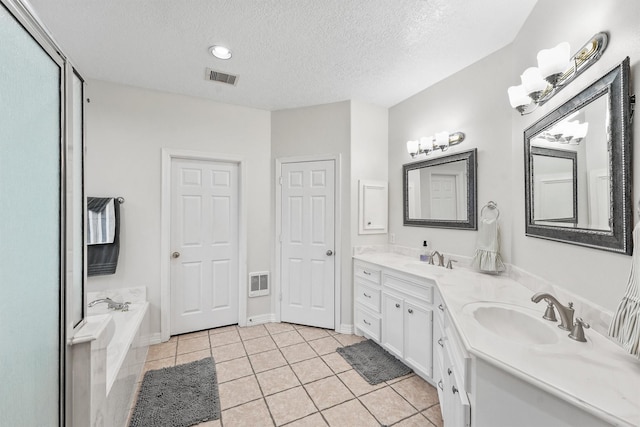 bathroom featuring a washtub, vanity, a textured ceiling, and tile patterned flooring