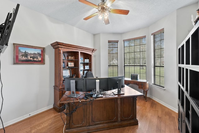 office area with ceiling fan, light wood-type flooring, and a textured ceiling