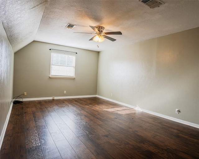 interior space with dark hardwood / wood-style floors, ceiling fan, a textured ceiling, and vaulted ceiling