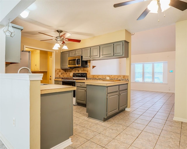 kitchen with kitchen peninsula, light tile patterned floors, range with electric stovetop, and ceiling fan