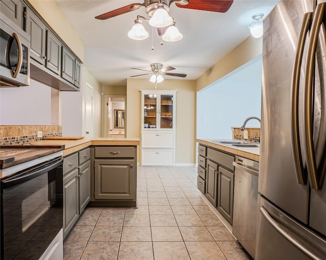 kitchen with gray cabinetry, backsplash, sink, and appliances with stainless steel finishes