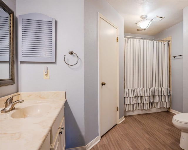 bathroom with a shower with shower curtain, hardwood / wood-style floors, vanity, and toilet