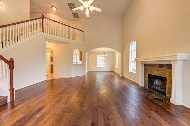 unfurnished living room featuring a fireplace, a high ceiling, dark hardwood / wood-style flooring, and ceiling fan