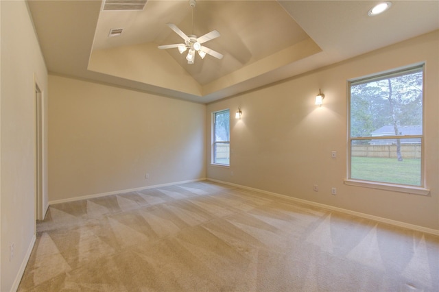 carpeted spare room with ceiling fan, a tray ceiling, and vaulted ceiling