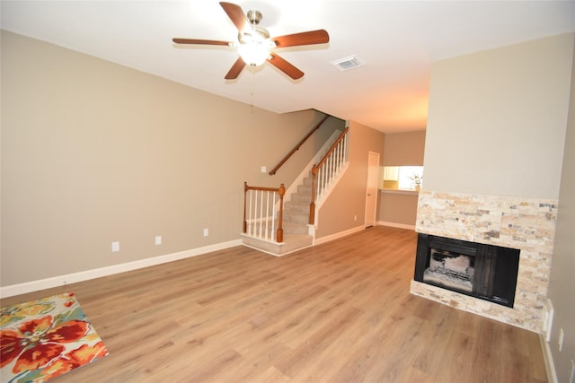 unfurnished living room featuring ceiling fan, a fireplace, and wood-type flooring