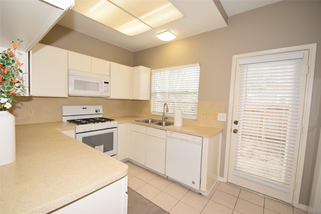 kitchen with tasteful backsplash, white appliances, sink, light tile patterned floors, and white cabinetry