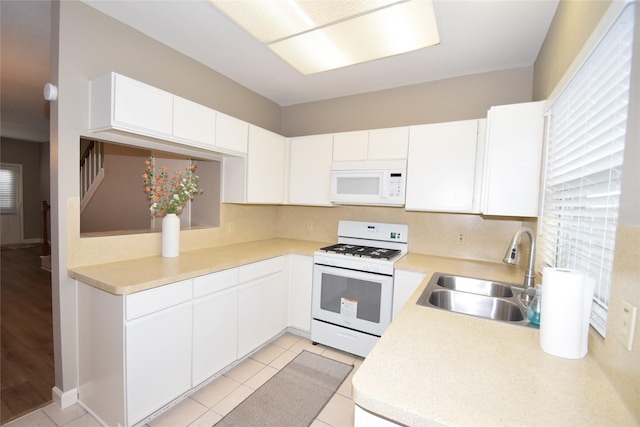 kitchen with white cabinetry, sink, light tile patterned floors, and white appliances