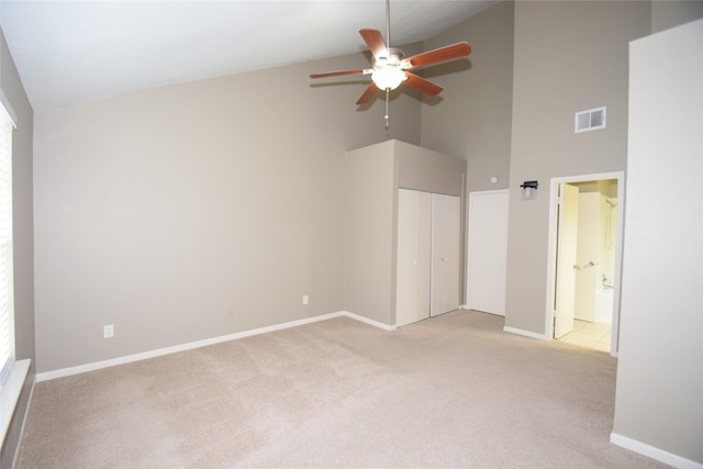 carpeted empty room with ceiling fan and high vaulted ceiling