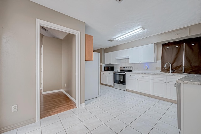 kitchen featuring stainless steel electric range oven, sink, white cabinets, white refrigerator, and light tile patterned floors