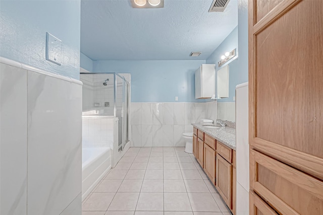 full bathroom featuring shower with separate bathtub, a textured ceiling, tile walls, vanity, and tile patterned flooring