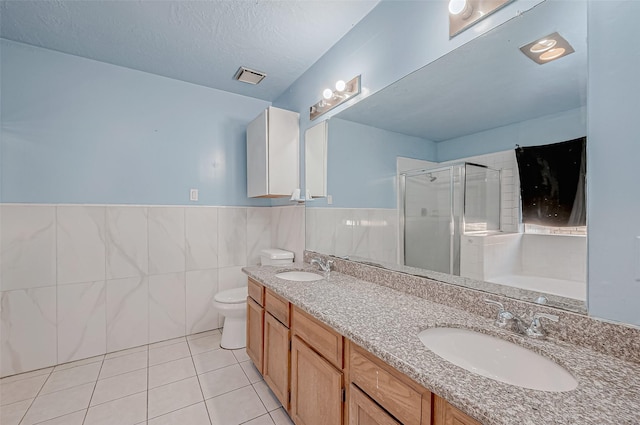 bathroom with tile walls, an enclosed shower, vanity, a textured ceiling, and tile patterned floors