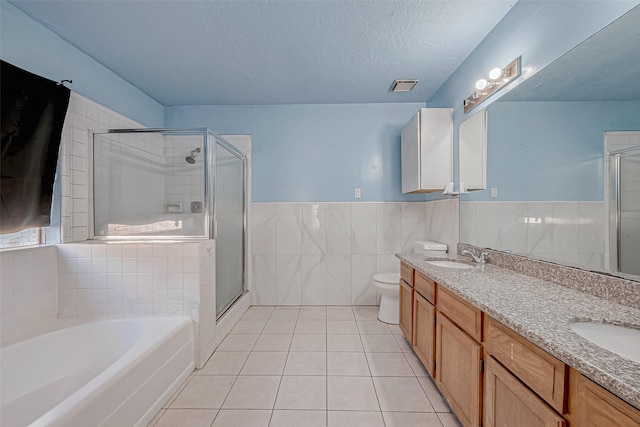 full bathroom with tile walls, a textured ceiling, tile patterned floors, shower with separate bathtub, and toilet